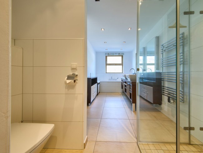 Modernes Badezimmer mit Dusche, Badewanne und Doppelwaschbecken in hellen Farbt&ouml;nen