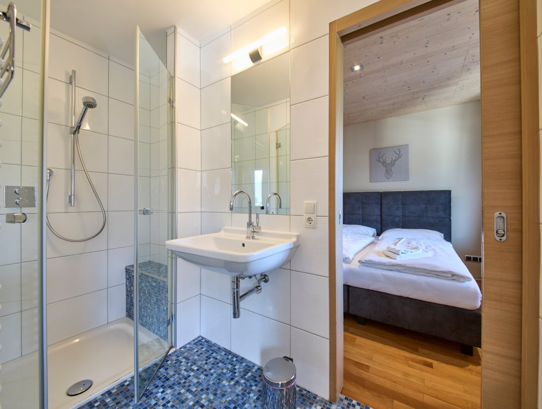 Modernes Badezimmer neben einem gem&uuml;tlichen Schlafzimmer mit Doppelbett